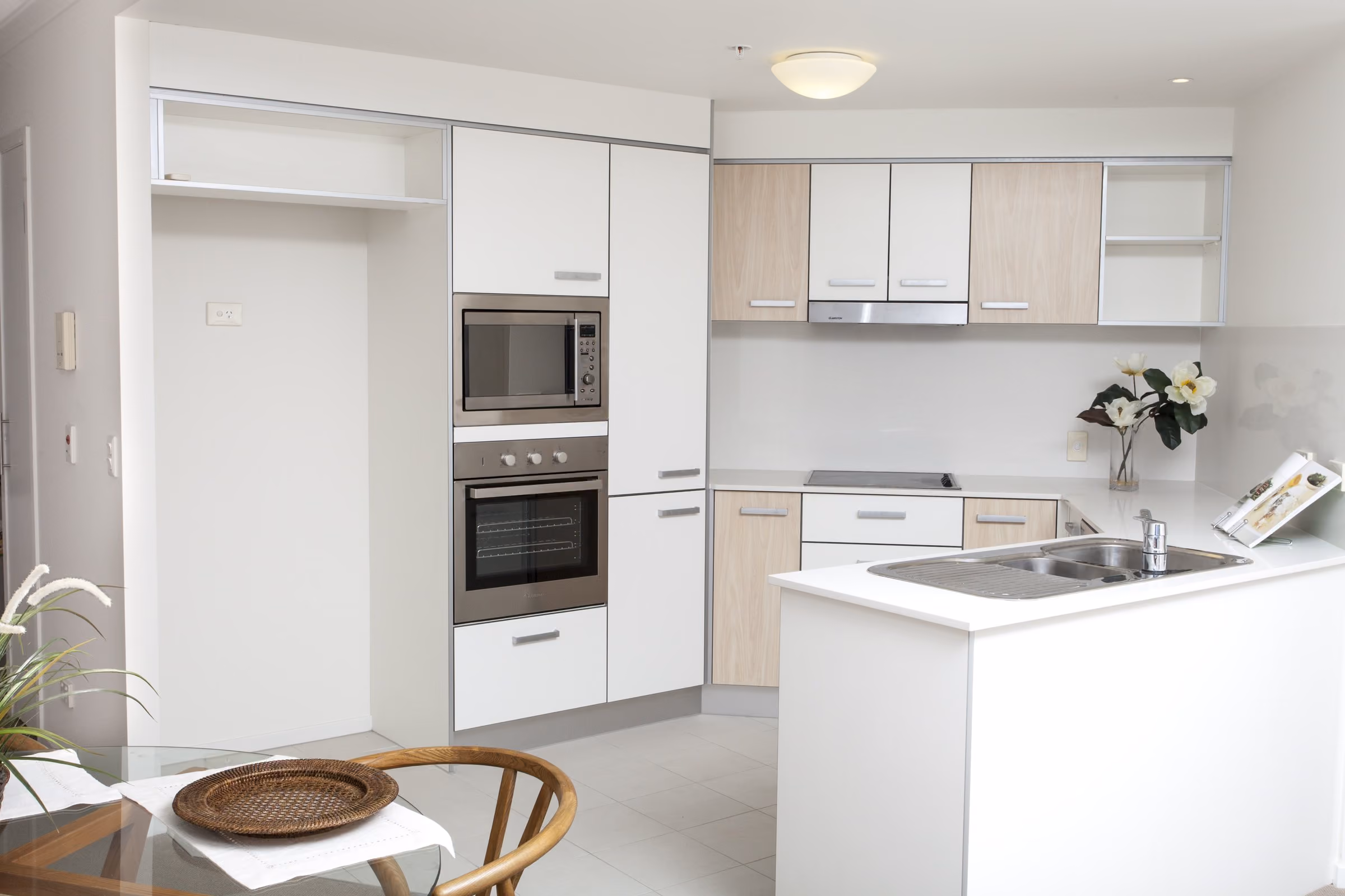 A white kitchen with an oven tower and stone benchtop