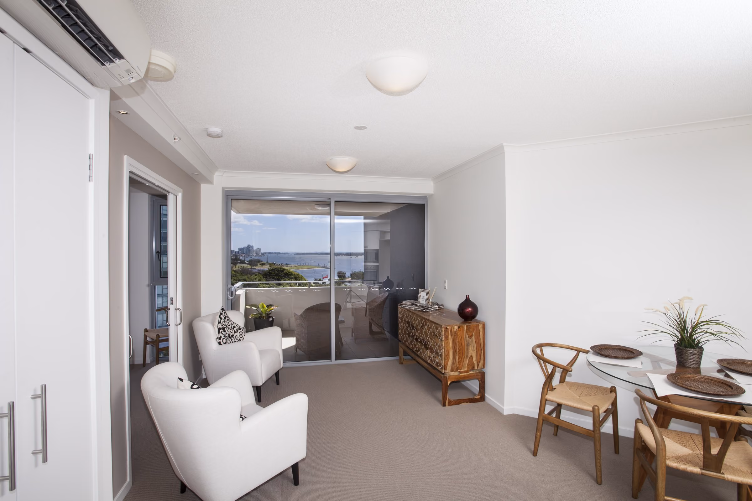 A furnished living and dining room with the Broadwater through the windows
