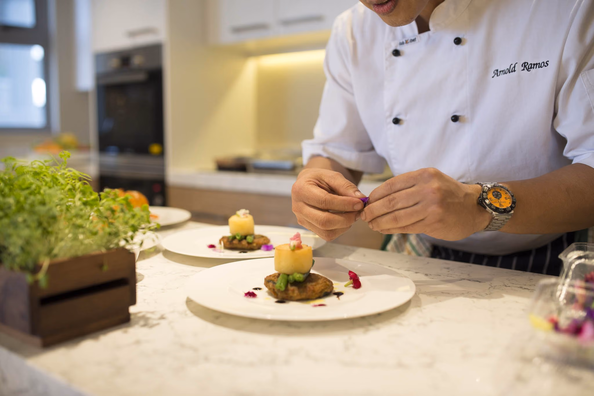 A chef plating a meal at the kitchen bench