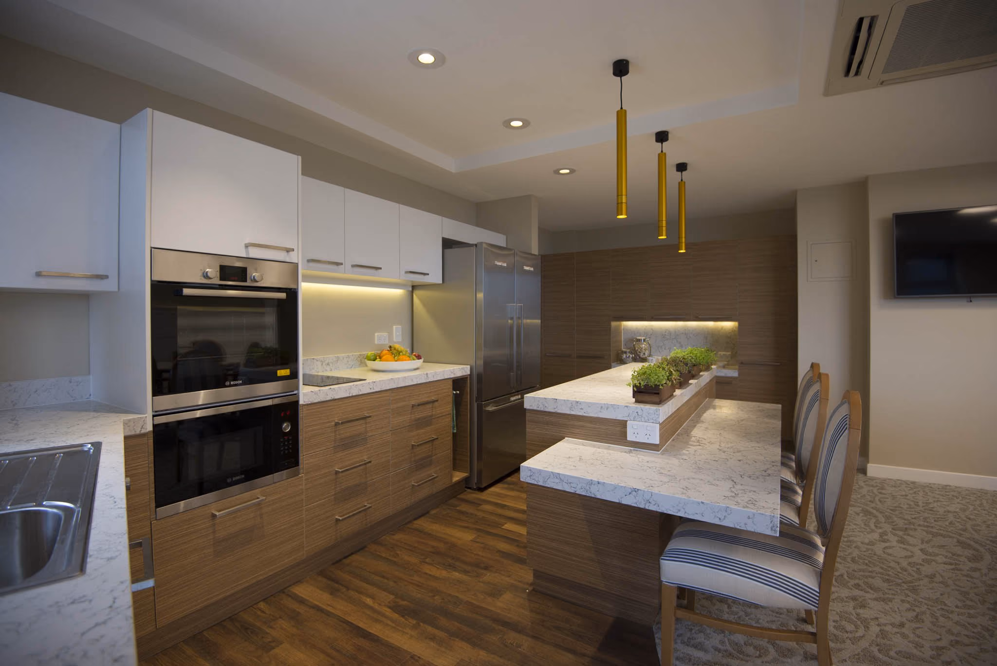 The household's open kitchen with a stone island and pendant lights