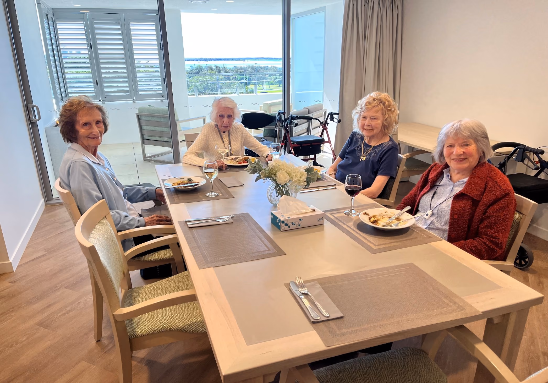Four residents at lunch in the refurbished Level 4 dining room, with the Broadwater through the windows behind them