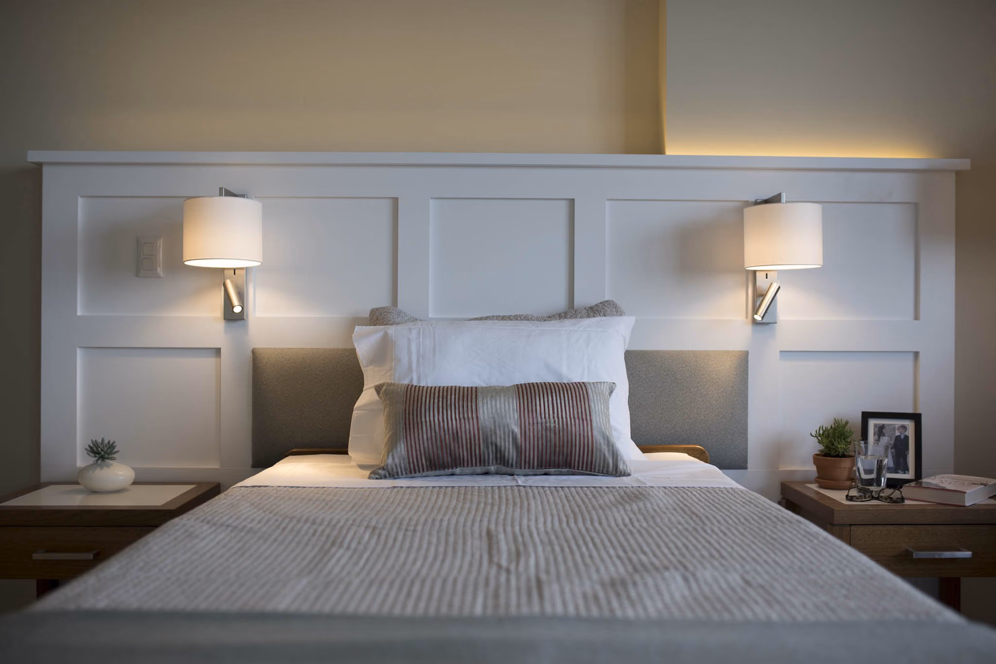 A made bed in a suite with a lamp and a framed picture